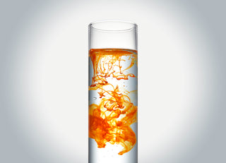 Science Tube with orange liquid mixing into clear liquid